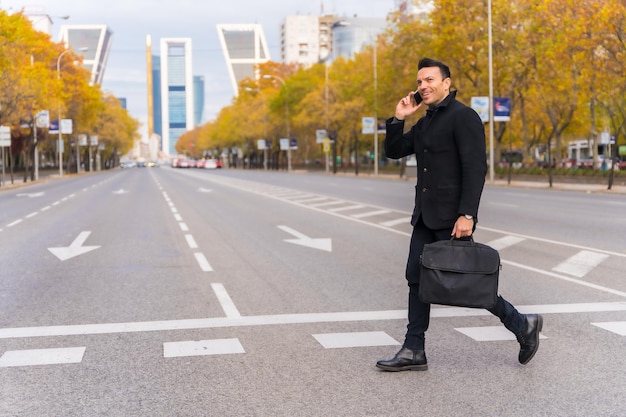 Middleaged Caucasian businessman talking on the phone at a city zebra crossing