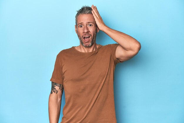 Photo middleaged caucasian man on blue backdrop being shocked she has remembered important meeting