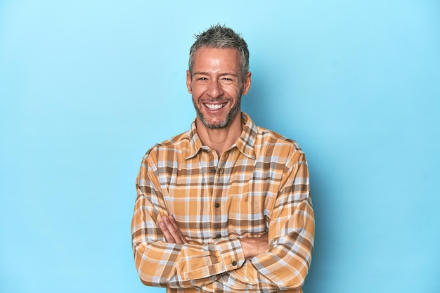 Photo middleaged caucasian man on blue backdrop laughing and having fun