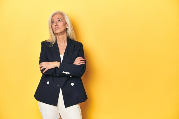 Middleaged Caucasian woman in business jacket yellow studio tired of a repetitive task