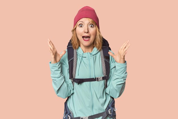 Middleaged Caucasian woman with hiking gear screaming to the sky looking up frustrated