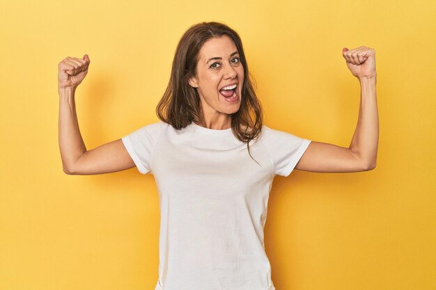 女性の力の象徴である腕を持つ強さのジェスチャーを示す黄色の中年の白人女性