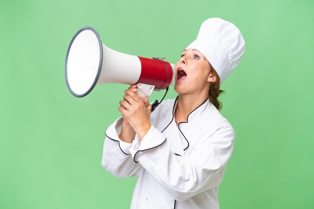 Middleaged chef woman over isolated background shouting through a megaphone