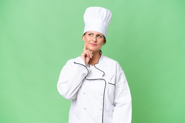 Middleaged chef woman over isolated background thinking an idea while looking up