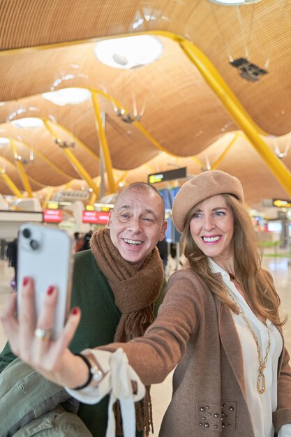 中年の恋人カップルは ⁇ 休暇のために飛行機に乗る前にスマートフォンで写真を撮ります ⁇ 