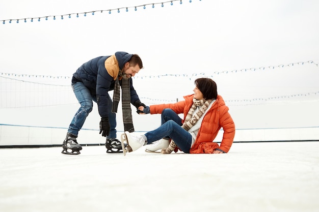 Middleaged couple man and woman having fun on outdoor icerink in winter day open air arena concept