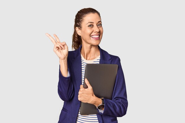 Photo middleaged entrepreneur with laptop in studio joyful and carefree showing a peace symbol