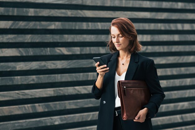 Middleaged female with ginger hair typing on smartphone