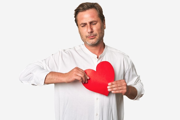 Middleaged gentleman radiates affection holding a paper heart in this sentimental studio portrait