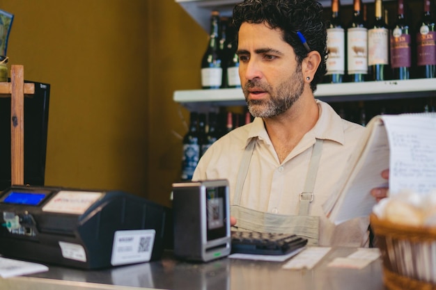 写真 中年ラテン系の男性ミニマーケットの起業家でキャッシュレジスタで会計をしています