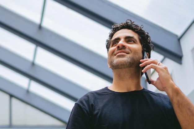 Photo middleaged latin man talking on the phone in a shed with a plastic roof copy space