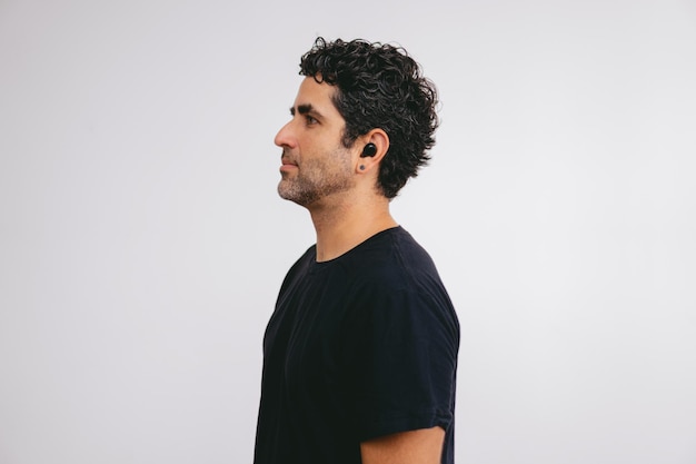 Middleaged Latin man with a wireless earphone posing for a pola photo on a white background