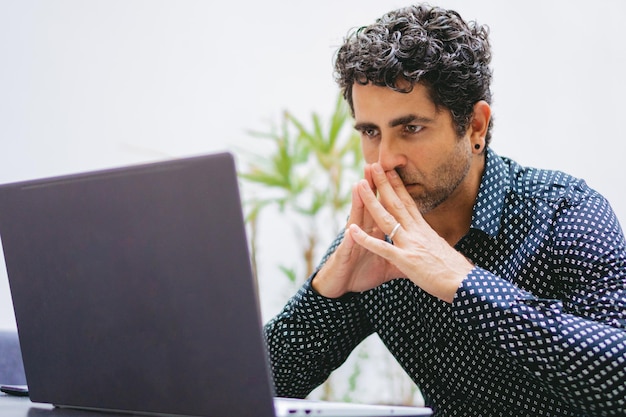 Middleaged Latin stockbroker in flamboyant shirt analyzing the market from his computer