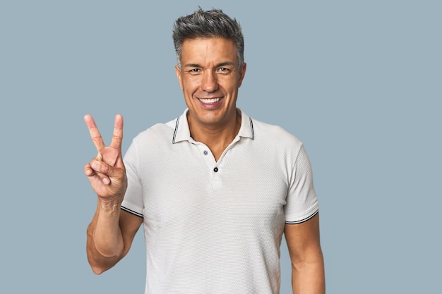 Middleaged Latino man showing victory sign and smiling broadly