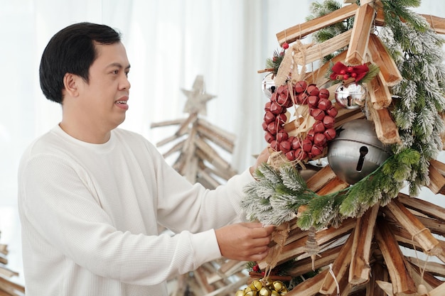 Middleaged man decorating christmas tree in living room