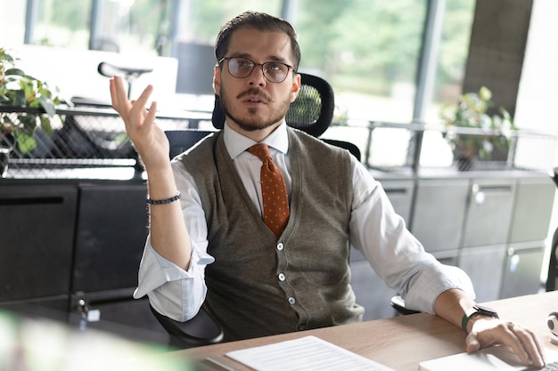 Middleaged man at a desk talking in an office with colleague smiling