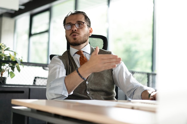 Middleaged man at a desk talking in an office with colleague smiling