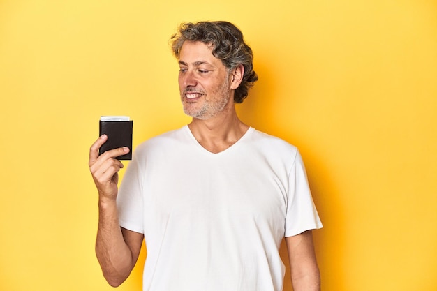 Middleaged man holding a wallet full of dollars denoting finance and wealth