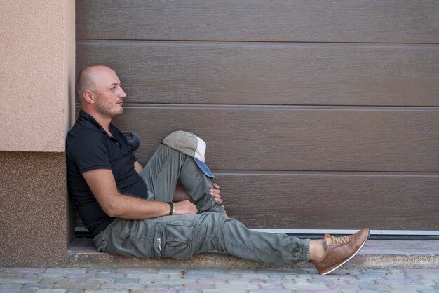A middleaged man is resting on the sidewalk Portrait of caucasian bald man outdoors