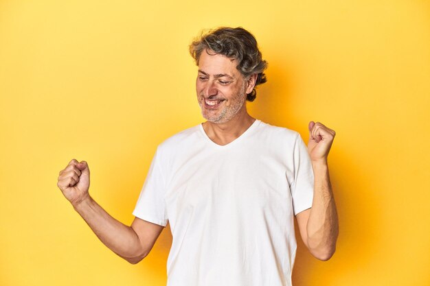 Middleaged man posing on a yellow backdrop dancing and having fun