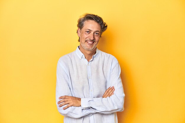 Middleaged man posing on a yellow backdrop laughing and having fun