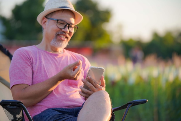 Middleaged man visits online dating site via sat on phone in flower garden focus on hand