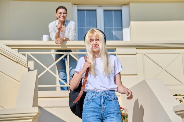 Middleaged mother seeing off her teenage daughter on the porch of the house