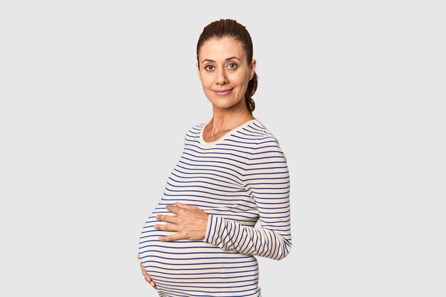 Middleaged pregnant woman glowing in studio