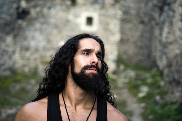 Middleaged sexy man with long hairstyle Sad frustrated man with long dark wavy hair and beard looking far away Portrait of handsome man with disappointed face