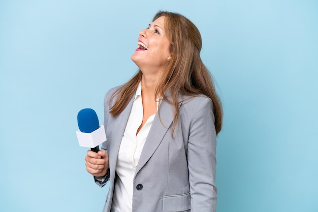 横位置で笑っている孤立した青い背景上の中年のテレビ司会者の女性