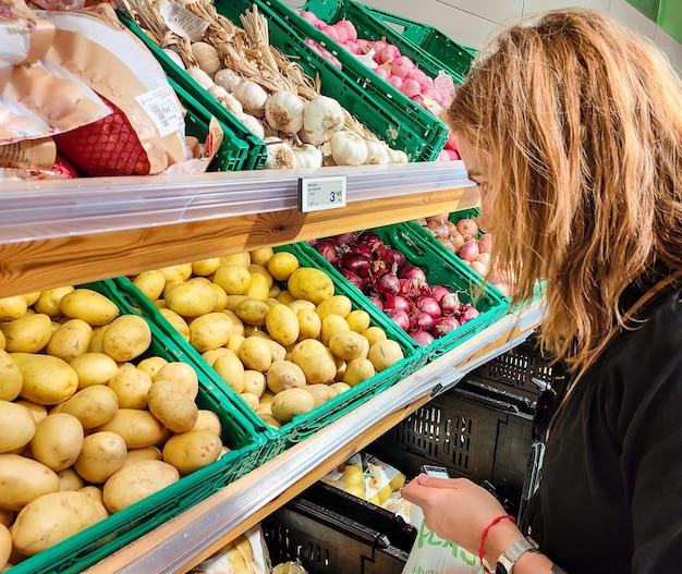 Middleaged woman choosing fruits vegetables and vegetables in her supermarket holding a bag