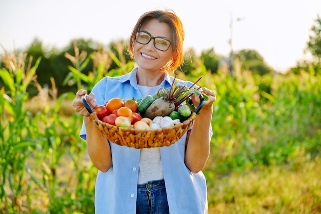 熟した野菜のバスケットを持つ中年女性の庭師農家