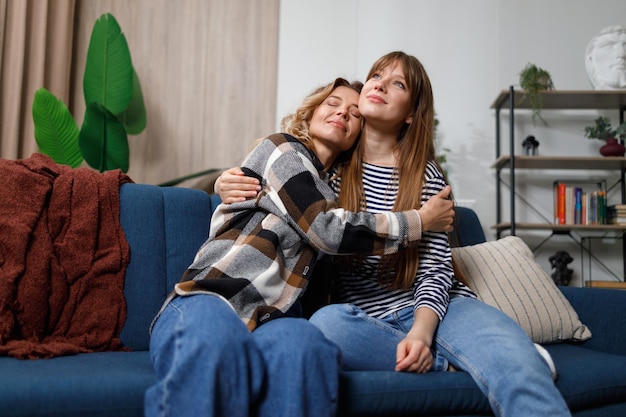 Middleaged woman hugging her adult daughter on the couch