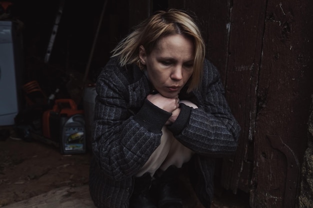 A middleaged woman is depressed on a dark background The woman sits and looks at the floor Middle age crisis