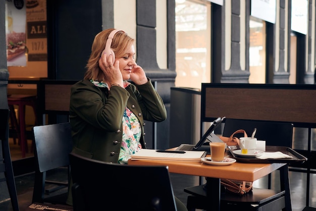 Middleaged woman listens to music while she is working from a\
coffee shop