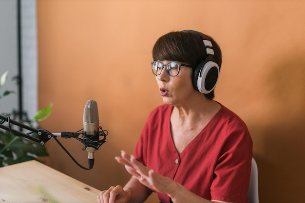 Радиоведущая женщина средних лет делает запись подкаста для онлайн-трансляции шоу и концепции диджея