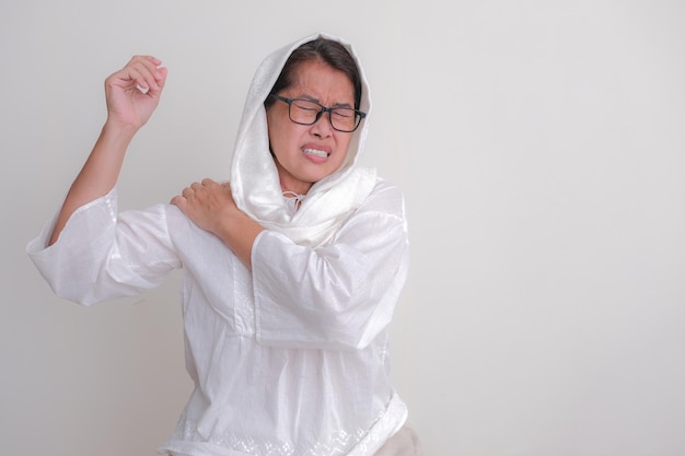 A middleaged woman touches her shoulder with pain expression