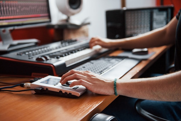 Midi-keyboard spelen. geluidstechnicus werkt en mixt muziek binnenshuis in de studio.