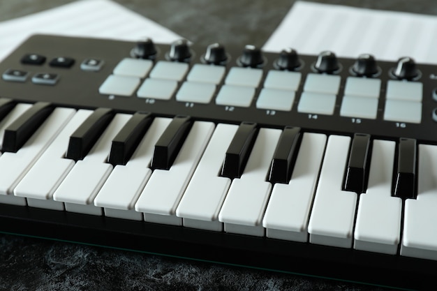 Midi-toetsenbord en muziekbladen op zwarte smokey-tafel