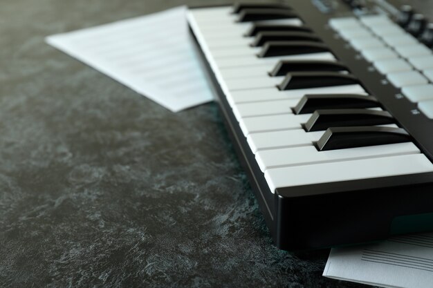 Midi-toetsenbord en muziekbladen op zwarte smokey-tafel