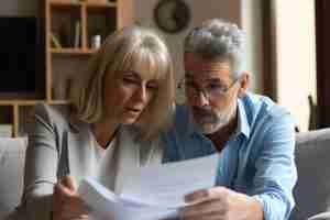 Photo midlife couple assiduously evaluating documentation contemplating mortgage insurance contract in th