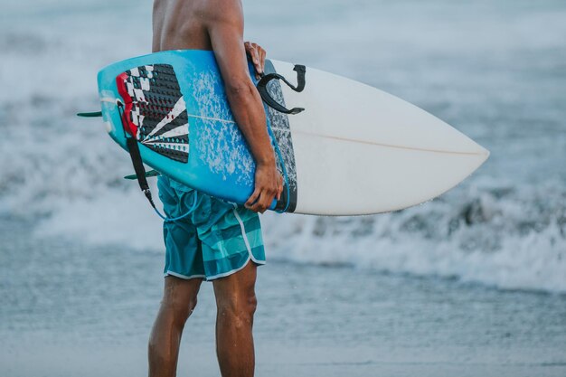 Foto midsectie van een man met een surfplank op het strand