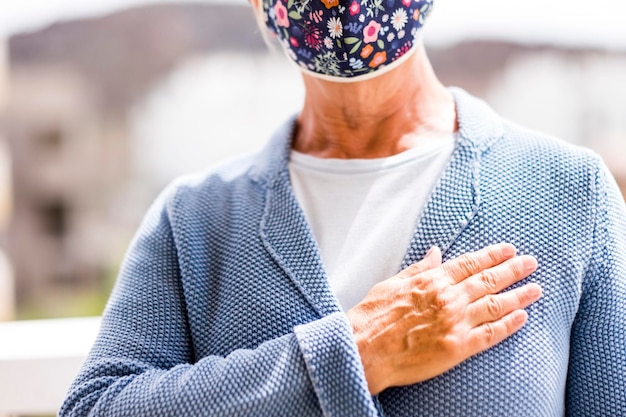 Foto midsectie van een oudere vrouw die een masker draagt en buiten staat en gebaren maakt