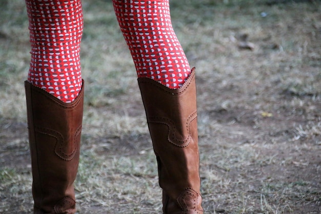 Foto midsectie van persoon die cowboy laarzen draagt op het veld