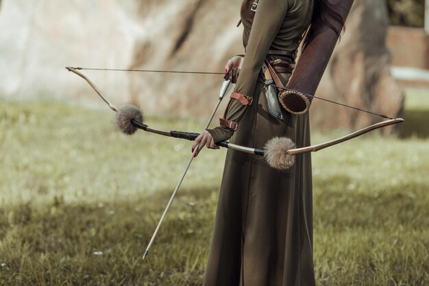 Photo midsection of archer holding bow and arrow while standing outdoors