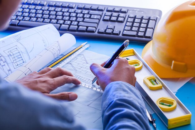 Photo midsection of architect drawing in blueprint on table