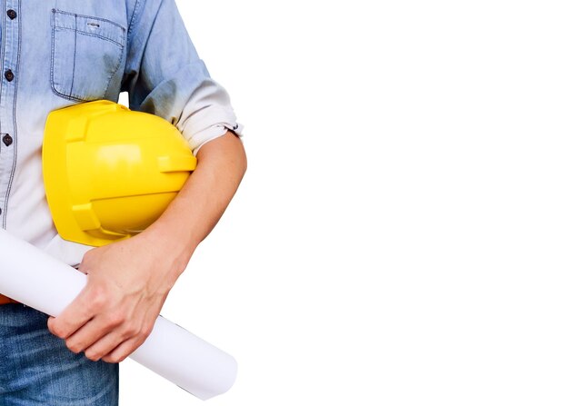 Midsection of architect holding hardhat and blueprint while standing against white background