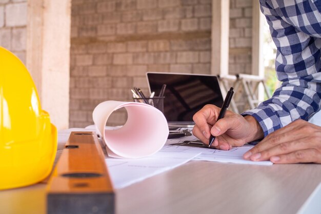 Midsection of architect writing in paper on desk