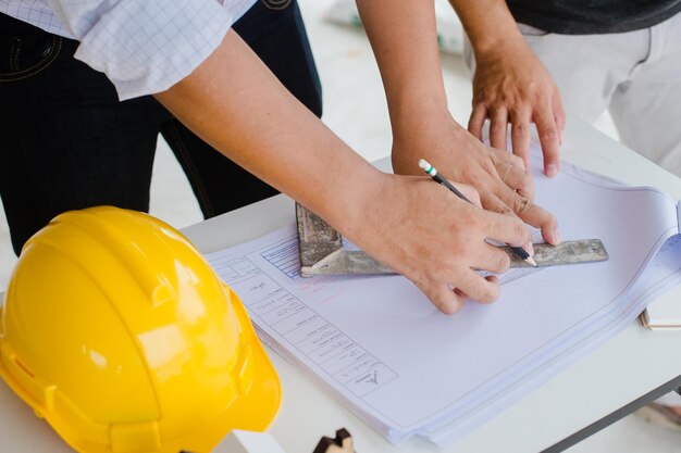 Midsection of architects working over blueprint at office