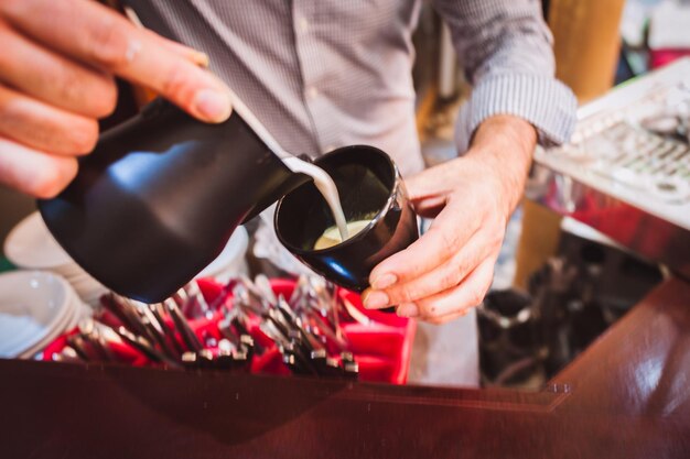 Foto sezione centrale di un barista che versa il caffè in una tazza da un contenitore in un caffè